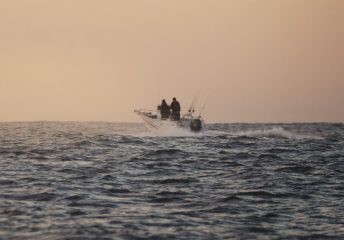 Offshore fishing boat cruising in the Pacific Ocean at sunset
